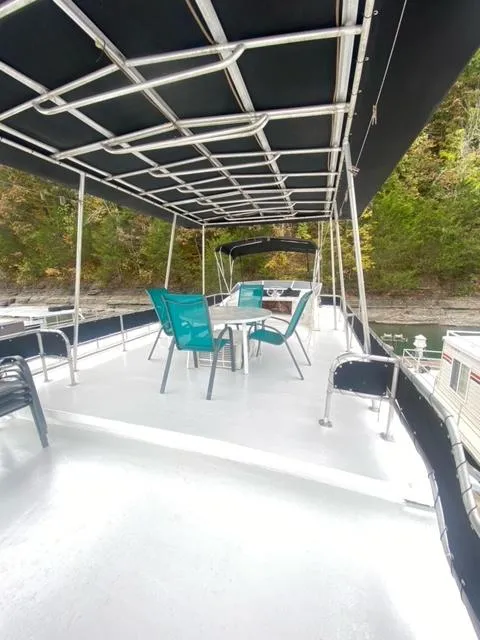 Slide: The Image of 1985 Arc houseboat deck with canopy, table, and chairs on a serene waterway. - 23