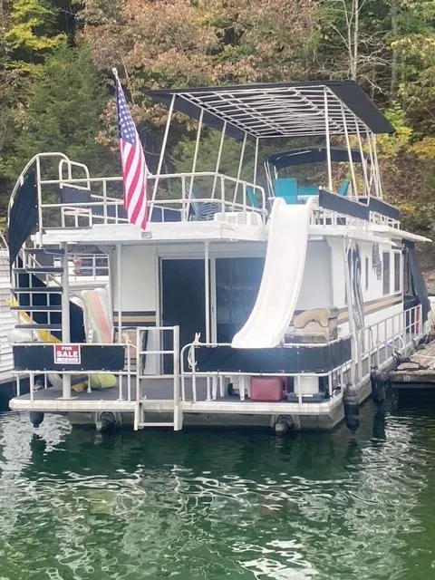 Slide: The Image of 1985 Arc houseboat with slide, American flag, docked on a serene lake. - 24