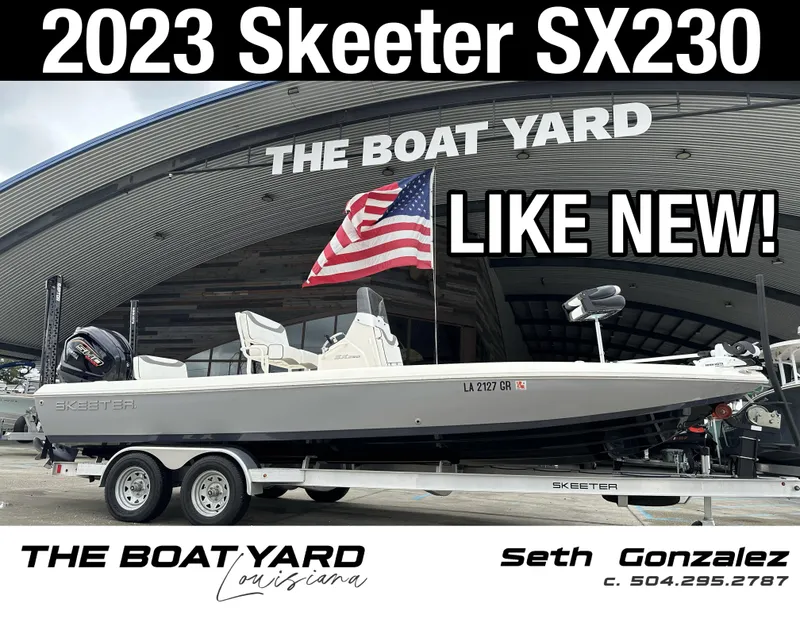 Slide: The Image of 2023 Skeeter SX230 boat at The Boat Yard, like new condition, displayed with American flag. - 1