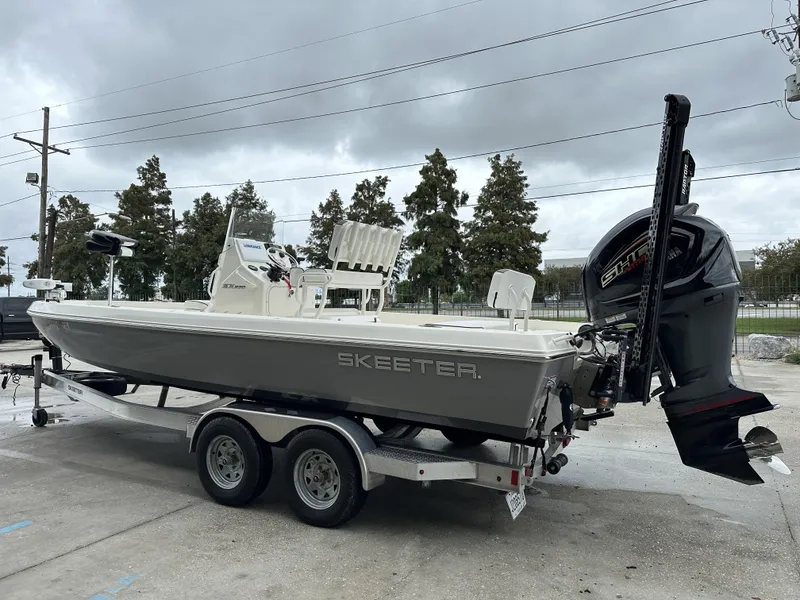 Slide: The Image of 2023 Skeeter SX230 boat on trailer, parked outdoors under cloudy sky. - 17