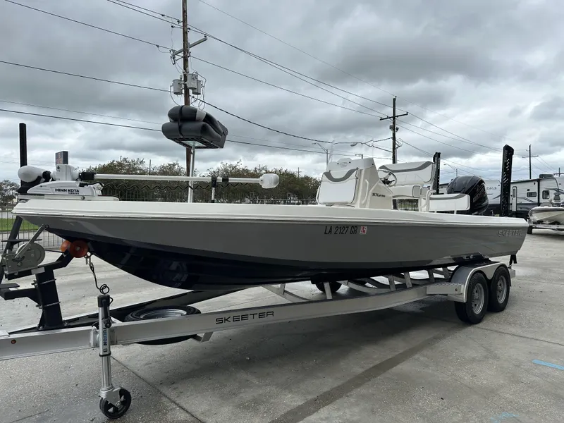 Slide: The Image of 2023 Skeeter SX230 boat on trailer, parked outdoors under cloudy skies. - 2