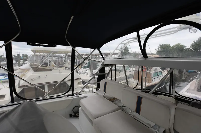 Slide: The Image of 1997 Mainship 34 Motor Yacht interior with marina view, featuring cushioned seating and large windows. - 15