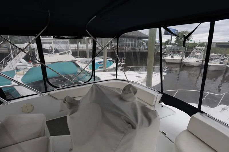 Slide: The Image of 1997 Mainship 34 Motor Yacht interior view at marina, showcasing helm and seating area. - 18