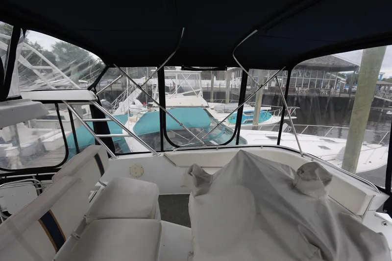 Slide: The Image of 1997 Mainship 34 Motor Yacht interior with marina view, featuring covered seating area. - 19