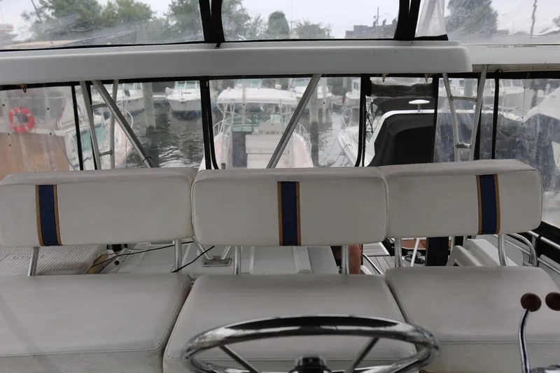 Slide: The Image of 1997 Mainship 34 Motor Yacht helm with white seating and marina view. - 39