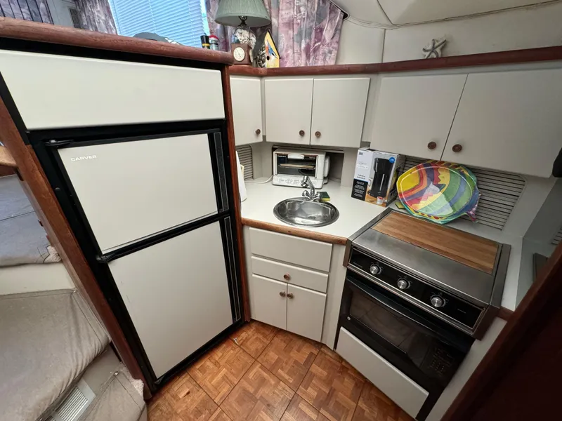 Slide: The Image of 1991 Carver 33 Aft Cabin kitchen with fridge, stove, and sink. - 26