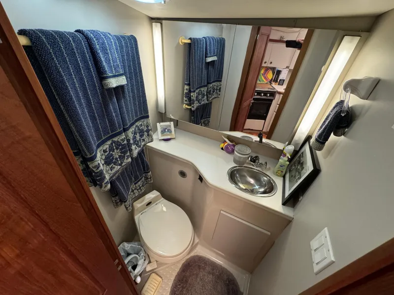 Slide: The Image of 1991 Carver 33 Aft Cabin bathroom with sink, toilet, and blue towels. - 27