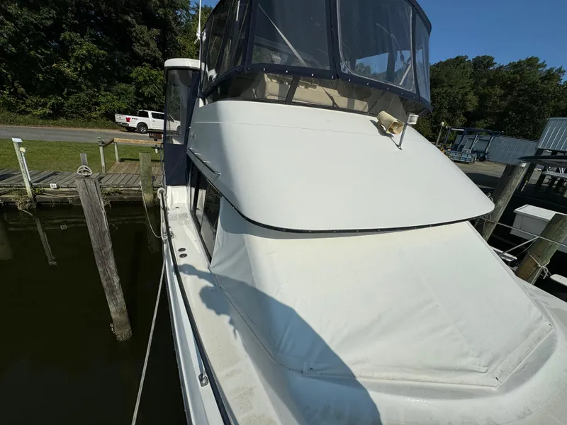 Slide: The Image of 1991 Carver 33 Aft Cabin boat docked, featuring covered upper deck and clear skies. - 8