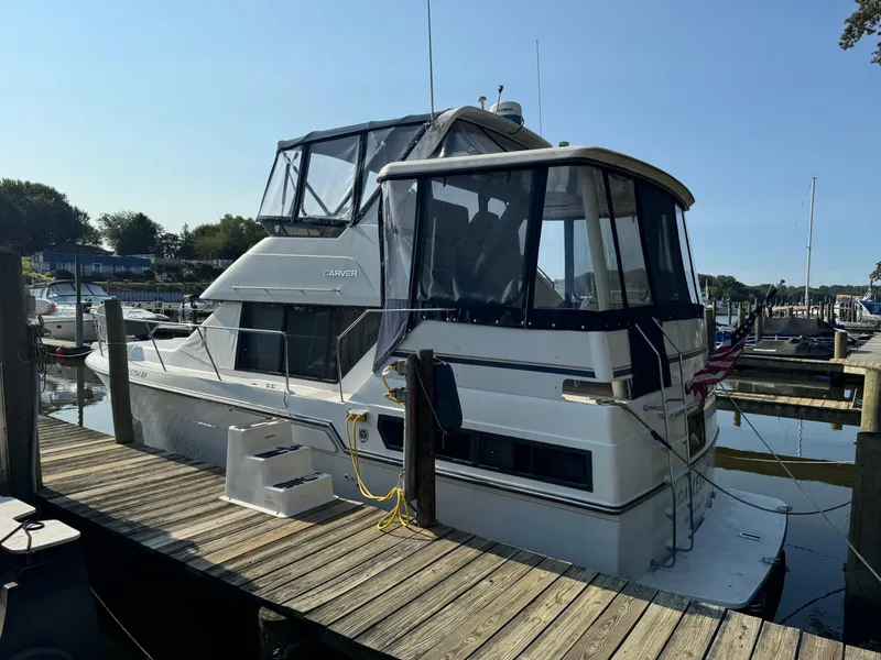 The Image of 1991 Carver 33 Aft Cabin yacht docked at marina under clear blue sky. - 1