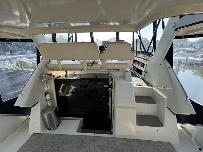 Slide: The Image of 1991 Carver 33 Aft Cabin interior with helm, seating, and stairs, overlooking marina. - 11