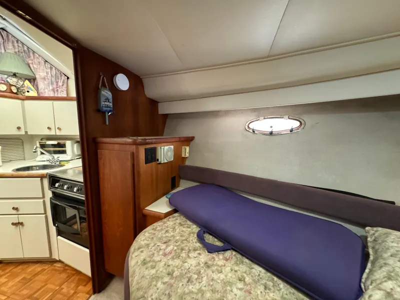 Slide: The Image of 1991 Carver 33 Aft Cabin interior with cozy bed, kitchenette, and wood accents. - 30