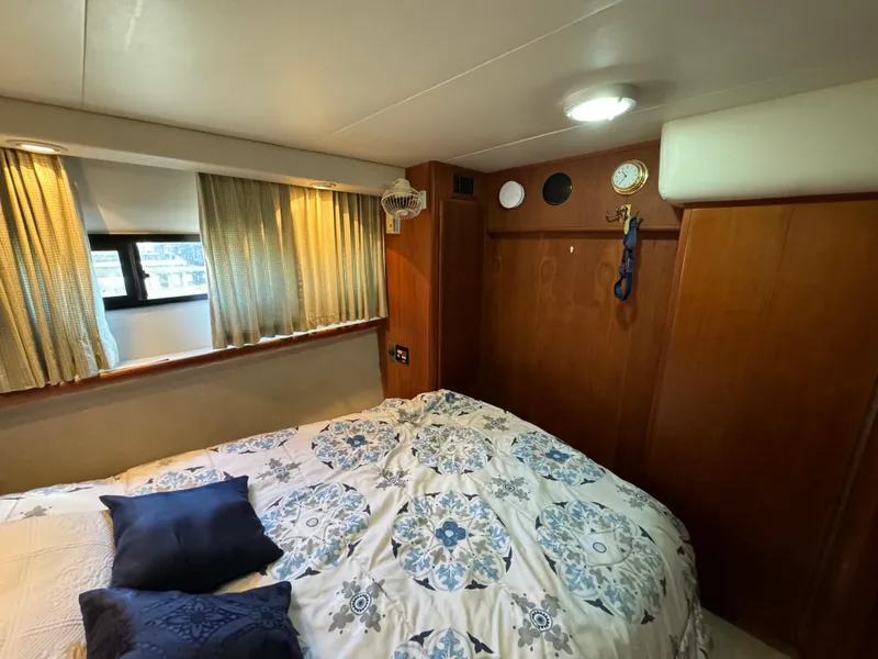 Slide: The Image of 1991 Carver 33 Aft Cabin bedroom with patterned bedding and wooden interior. - 33