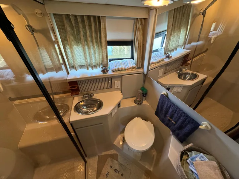 Slide: The Image of 1991 Carver 33 Aft Cabin bathroom with sink, toilet, and shower, featuring curtains and mirror. - 35