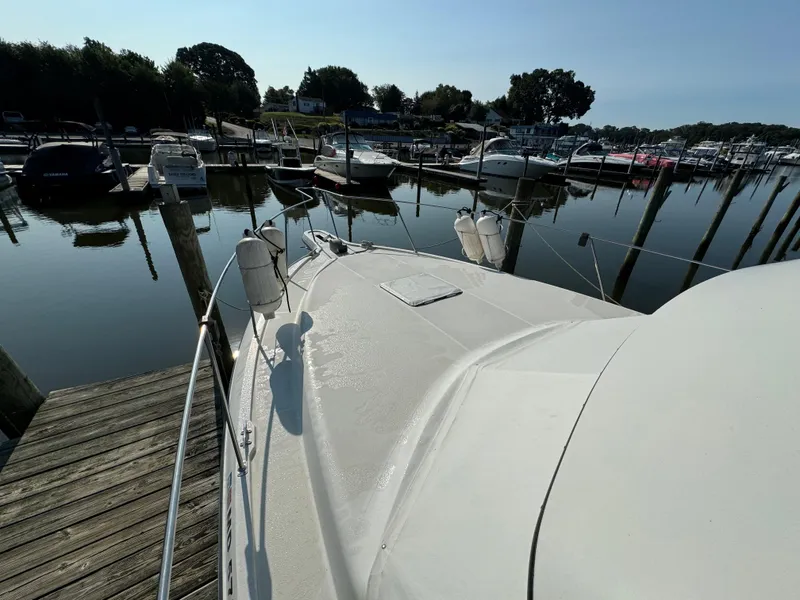 Slide: The Image of 1991 Carver 33 Aft Cabin yacht docked at a marina, surrounded by calm water and boats. - 5