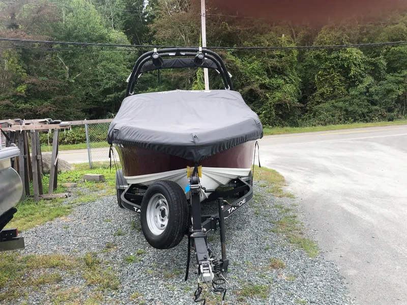 Slide: The Image of 2022 Tahoe 185 S boat on trailer, covered, parked on gravel near trees. - 3