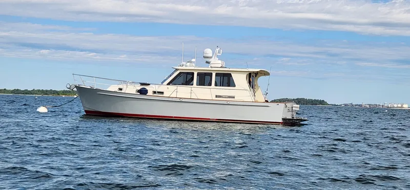 Slide: The Image of Legacy 42 boat from 2005 on calm water under a partly cloudy sky. - 0