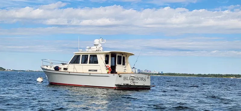 Slide: The Image of Legacy 42 boat from 2005 on calm water under a partly cloudy sky. - 2