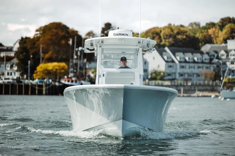 Slide: The Image of 2024 Onslow Bay 27XS boat cruising on water near coastal town. - 21