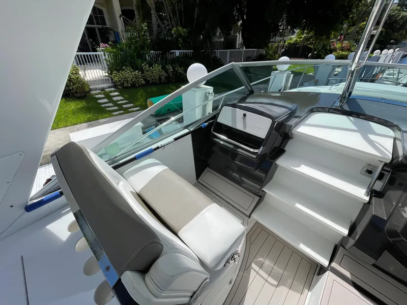 Slide: The Image of 2016 Monterey 335 Sport Yacht cockpit with seating and helm, surrounded by lush greenery. - 5