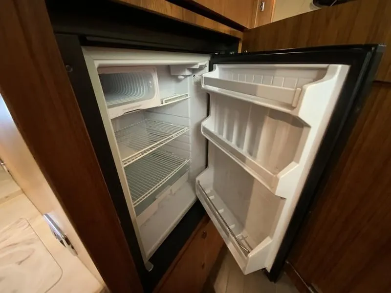Slide: The Image of Open refrigerator inside 2013 Tiara Yachts 36, showcasing spacious interior and shelving. - 26