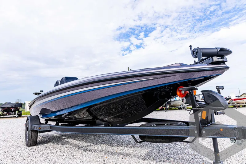 Slide: The Image of 2025 Skeeter ZX 150 boat on trailer, parked on gravel under a cloudy sky. - 10