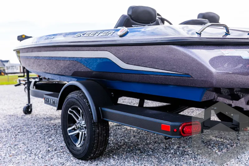 Slide: The Image of 2025 Skeeter ZX 150 boat on trailer, sleek design, parked on gravel. - 24