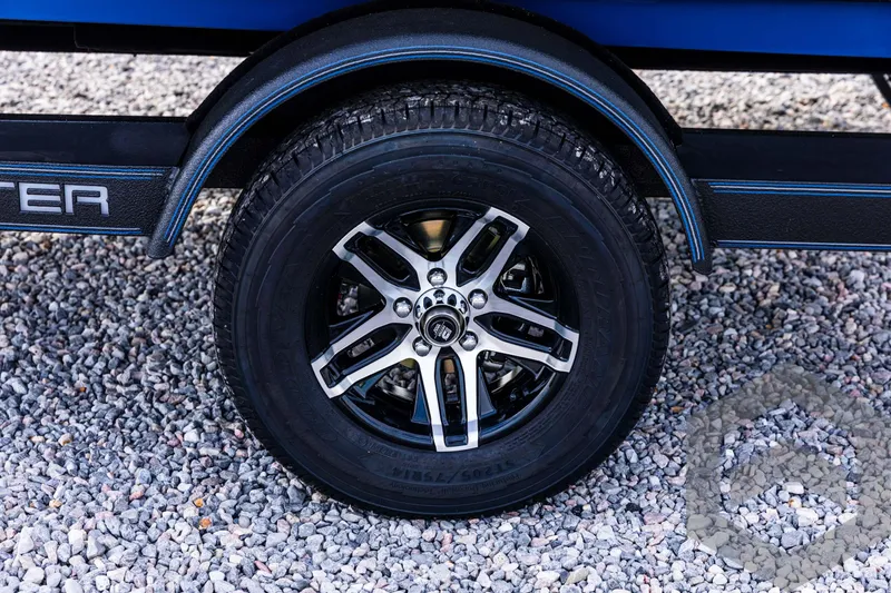 Slide: The Image of 2025 Skeeter ZX 150 trailer wheel on gravel surface. - 26