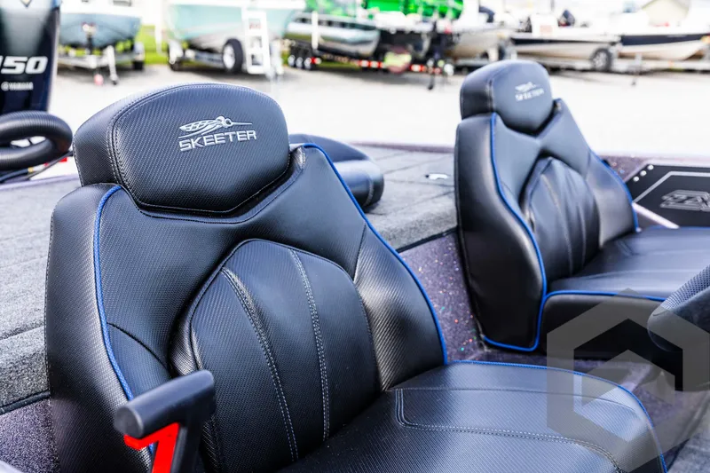 Slide: The Image of 2025 Skeeter ZX 150 boat seats, black leather with blue accents, in a showroom setting. - 36