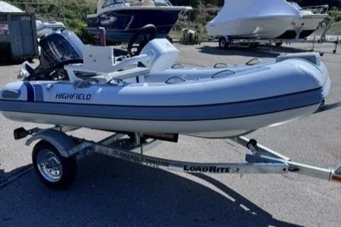 Slide: The Image of 2024 Highfield Classic 310 FCT inflatable boat on LoadRite trailer in marina setting. - 0