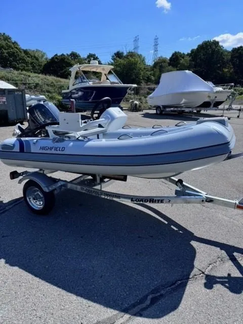 Slide: The Image of 2024 Highfield Classic 310 FCT inflatable boat on a trailer in a marina. - 2