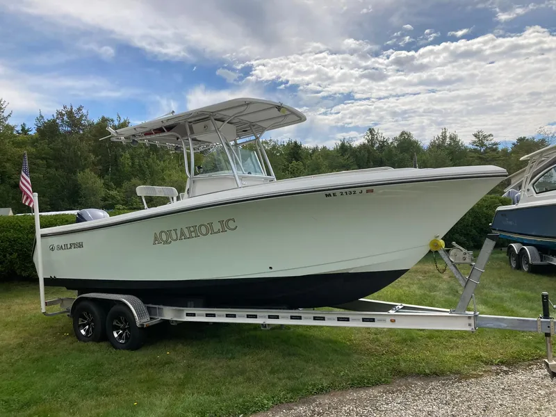 Slide: The Image of 2011 Sailfish 2360 CC boat on trailer, parked on grass under cloudy sky. - 3