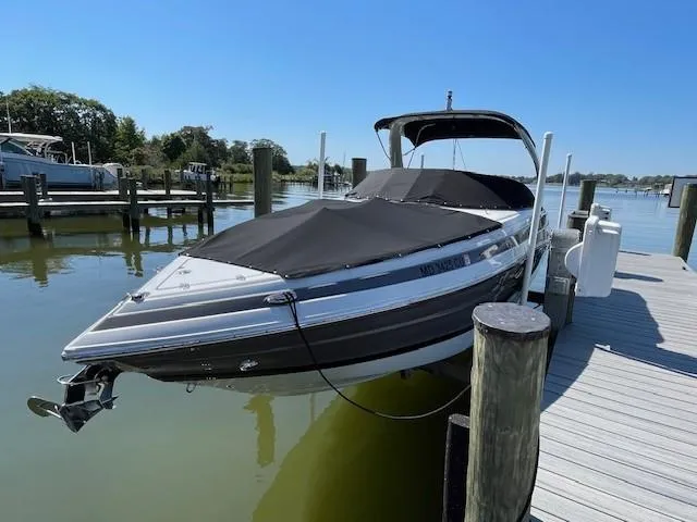 Slide: The Image of 2023 Crownline 290 XSS boat docked at marina under clear blue sky. - 0