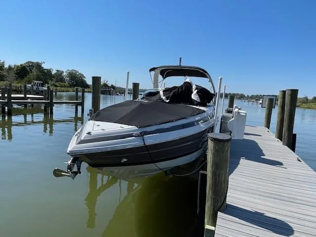 Slide: The Image of 2023 Crownline 290 XSS boat docked on a sunny day. - 2