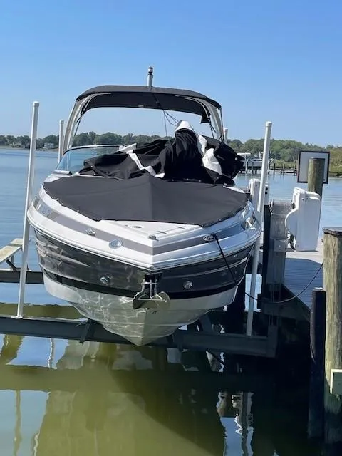 Slide: The Image of 2023 Crownline 290 XSS boat docked on a lift by the water. - 3