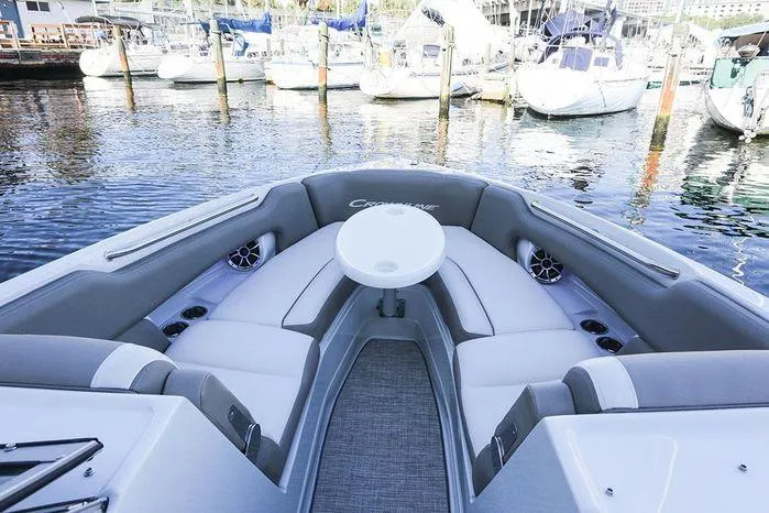 Slide: The Image of 2023 Crownline 290 XSS boat interior with seating and table, docked at marina. - 32