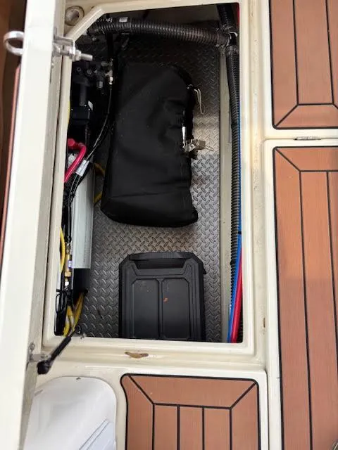 Slide: The Image of 2023 Ranger Tugs R-29 S storage compartment with equipment and wiring on a textured floor. - 25