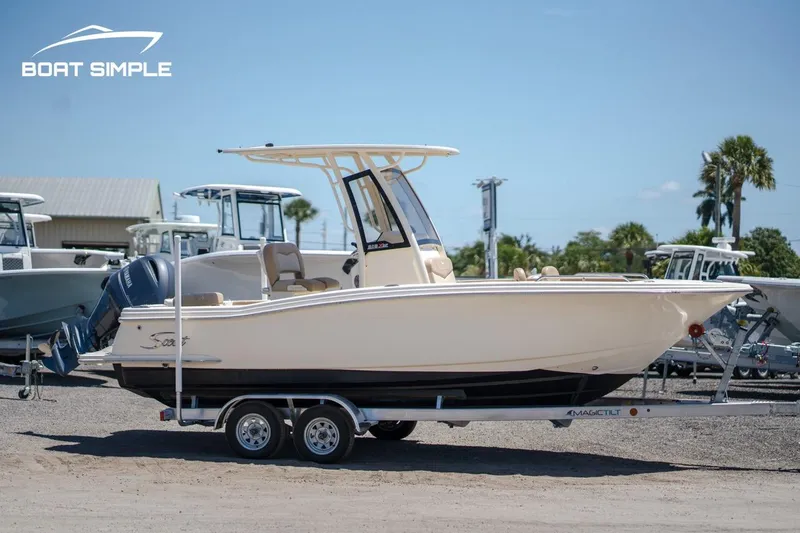 Slide: The Image of 2023 Scout 215 XSF boat on trailer, parked outdoors under clear sky. - 1