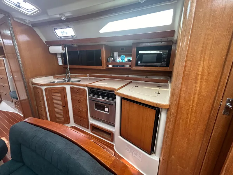 Slide: The Image of 1998 Catalina 42 MkII yacht interior kitchen with wood cabinetry and modern appliances. - 23