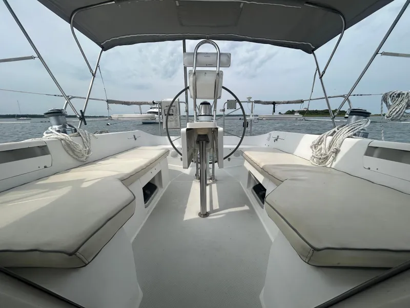 Slide: The Image of 1998 Catalina 42 MkII sailboat cockpit with dual seating and steering wheel, docked on calm water. - 7