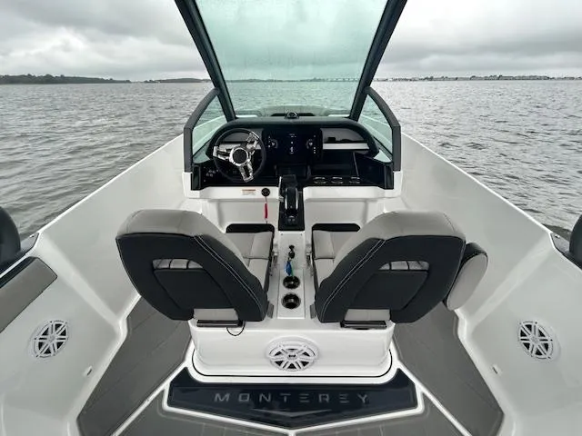 Slide: The Image of 2025 Monterey 27 Elite boat interior with dual seats and steering, on a calm lake. - 4