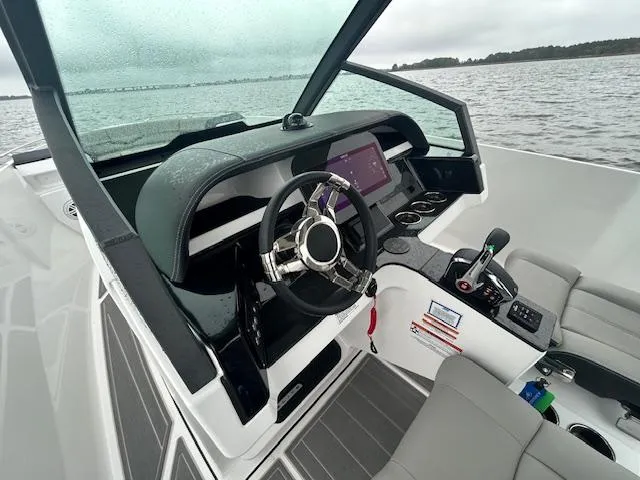 Slide: The Image of 2025 Monterey 27 Elite boat cockpit with modern steering and controls on a lake. - 5