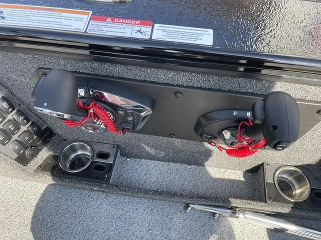 Slide: The Image of Control panel of 2025 Lund 2075 Pro-V Sport boat with throttle levers and cup holders. - 27