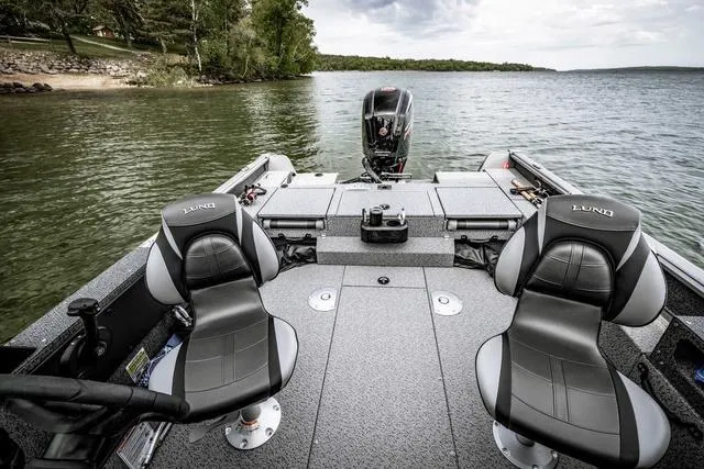 Slide: The Image of 2025 Lund 1775 Impact XS Sport boat interior with two seats on a lake. - 3