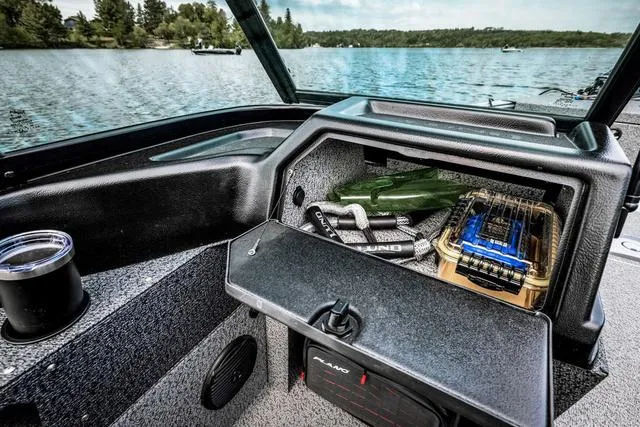 Slide: The Image of 2025 Lund 1775 Impact XS Sport boat interior with storage compartment on a lake. - 8