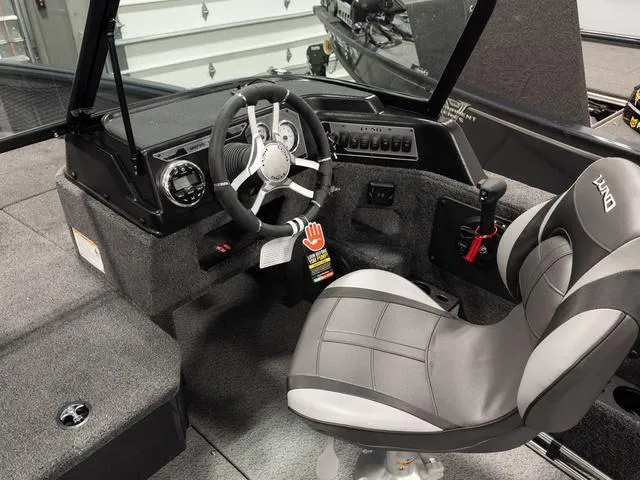 Slide: The Image of 2025 Lund 1875 Impact XS boat interior with steering wheel and captain's seat. - 8