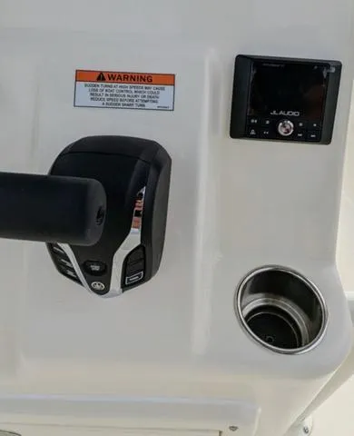 Slide: The Image of 2025 Cobia 220 CC boat, blue and white canopy, parked outside a building. - 19