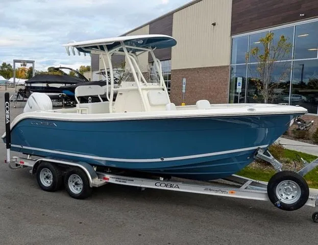 Slide: The Image of 2025 Cobia 220 CC boat on trailer, blue hull, parked outdoors. - 4