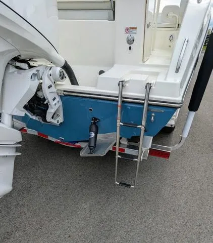 Slide: The Image of 2025 Cobia 220 CC boat with white seating and center console in a parking lot. - 9