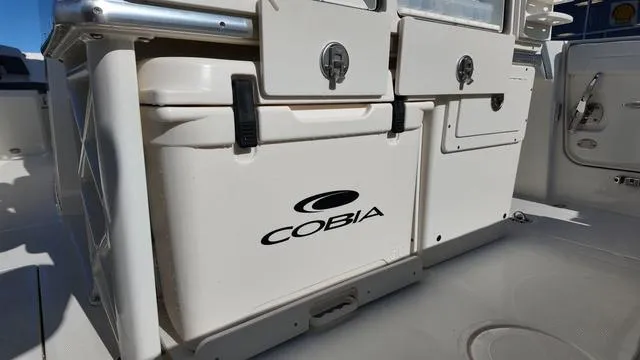 Slide: The Image of 2025 Cobia 265 CC boat interior with storage compartments and logo. - 12