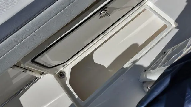 Slide: The Image of 2025 Cobia 265 CC boat storage compartment with open lid. - 13